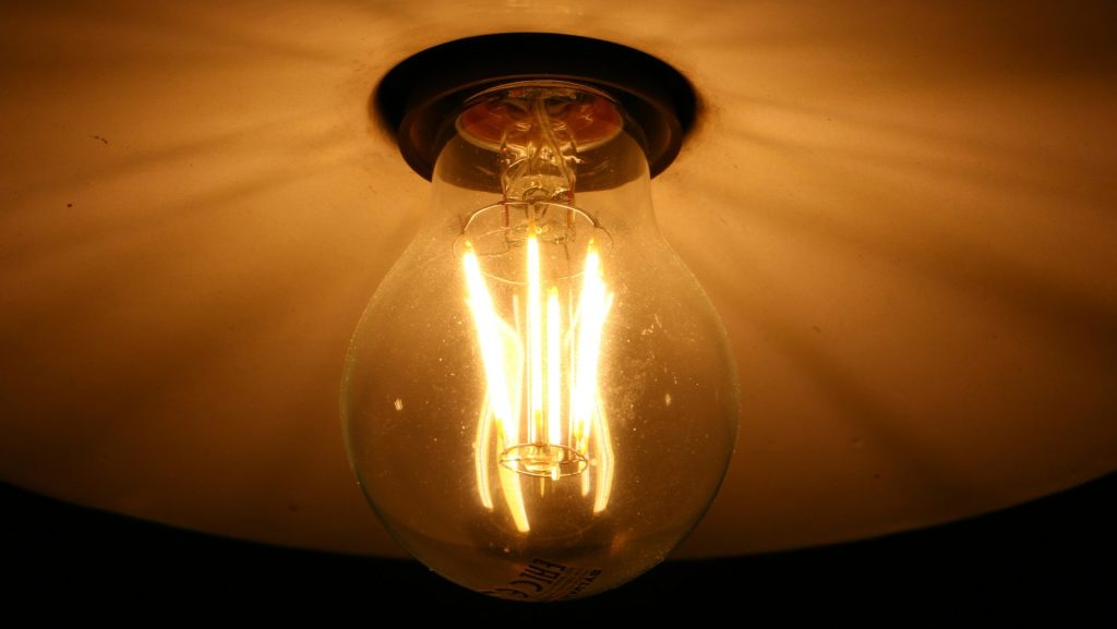 clear glass light bulb turned on on white textile